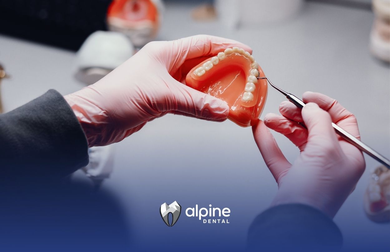 Dentist examines denture model with tools, showing reline adjustments and demonstrating the process in a clinical setting.
