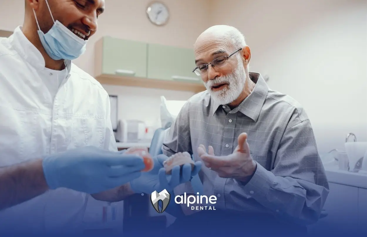 Dentist explaining dentures and dental implant options to an elderly patient during a consultation in a modern dental clinic.