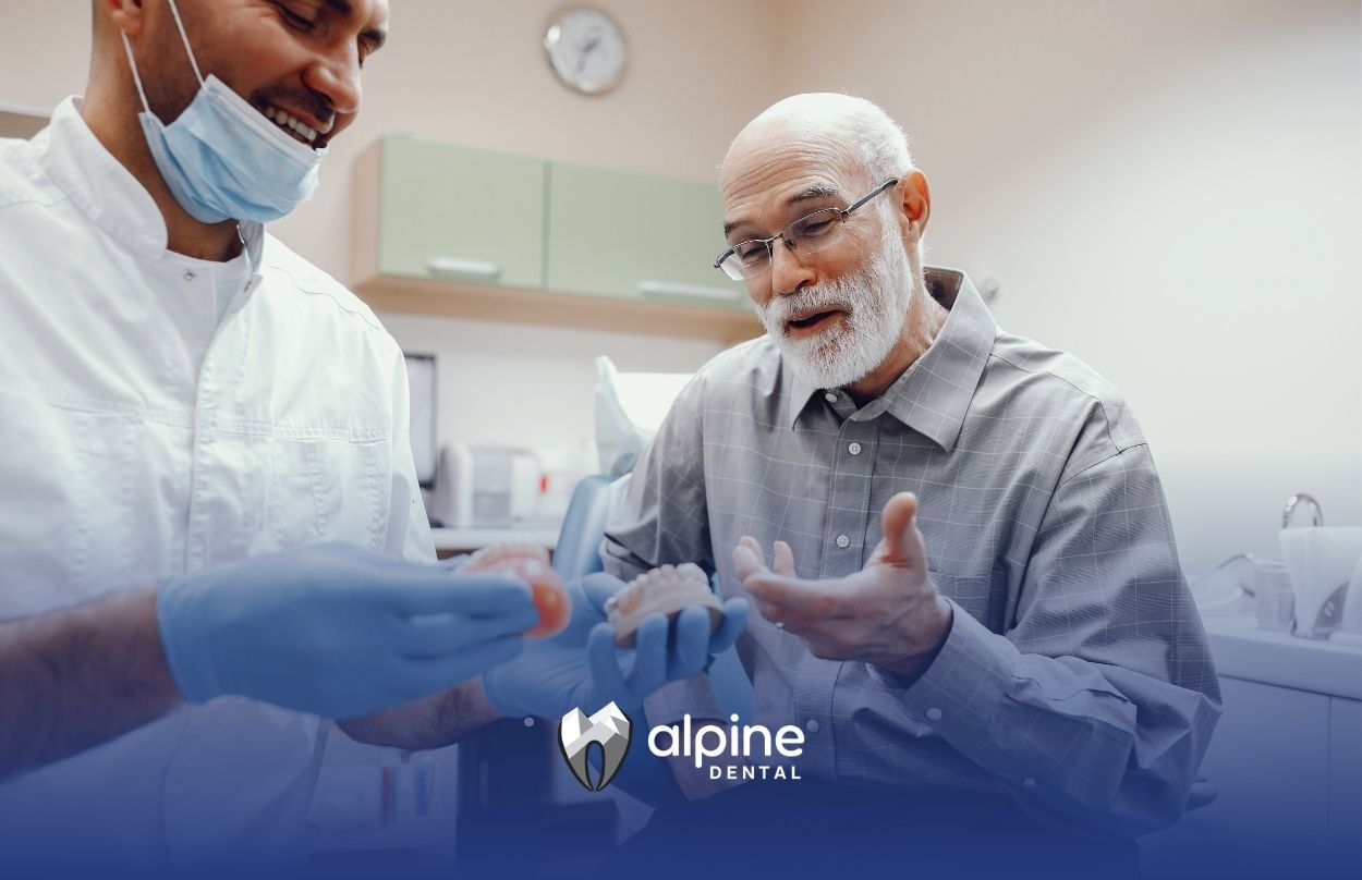 Dentist explaining dentures and dental implant options to an elderly patient during a consultation in a modern dental clinic.