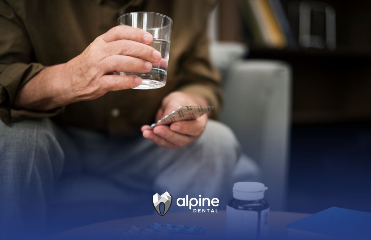 Person taking medication with water and pills, showing how heart meds link dry mouth to dental health concerns.